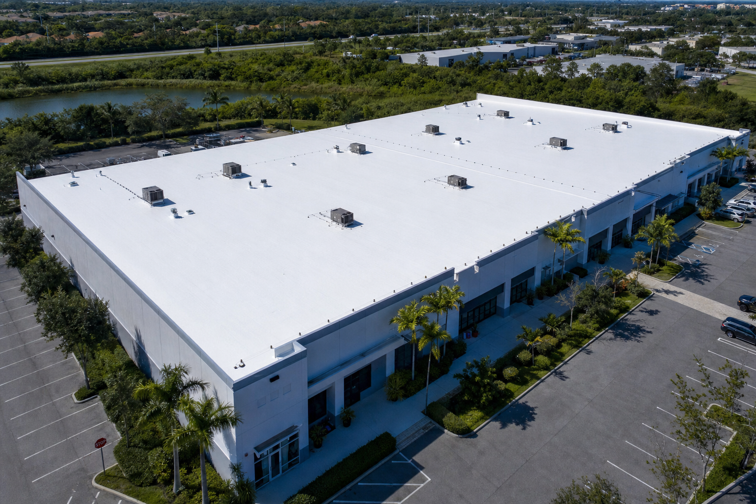 White silicone roof coating on large Florida commercial building — aerial view