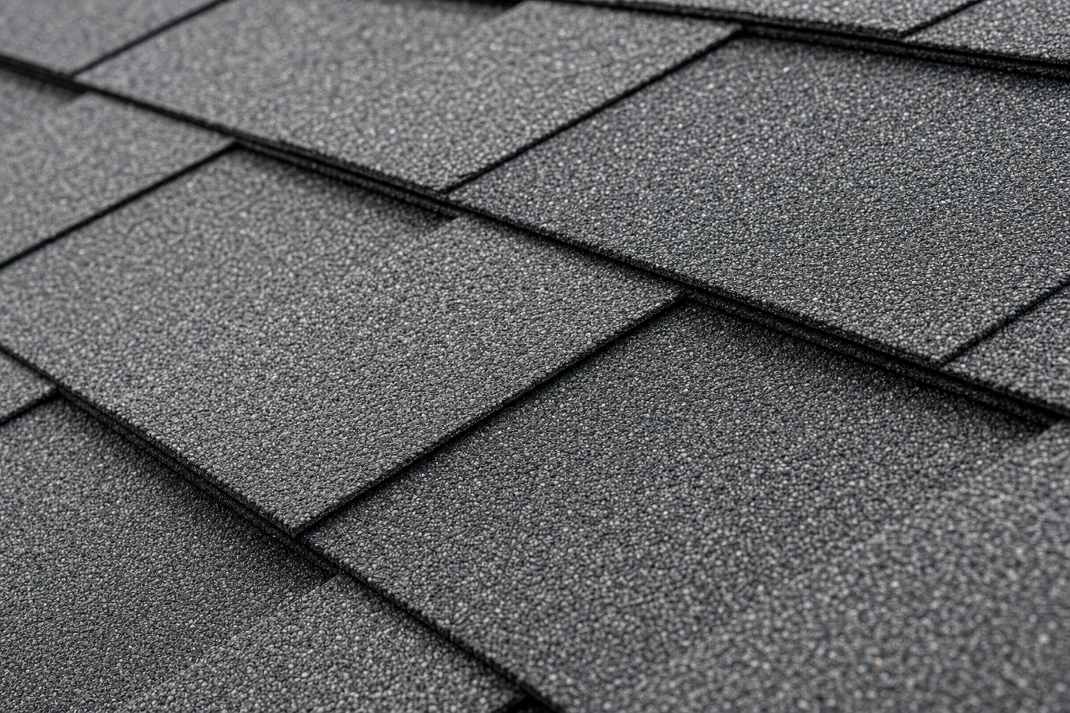 Close-up of asphalt shingle granule texture, charcoal gray